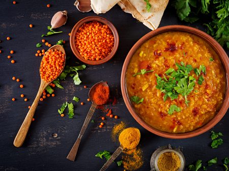 Indian dal. Food. Traditional Indian soup lentils.  Indian Dhal spicy curry in bowl, spices, herbs, rustic black wooden background. Top view. Authentic Indian dish. Overhead. Flat lay